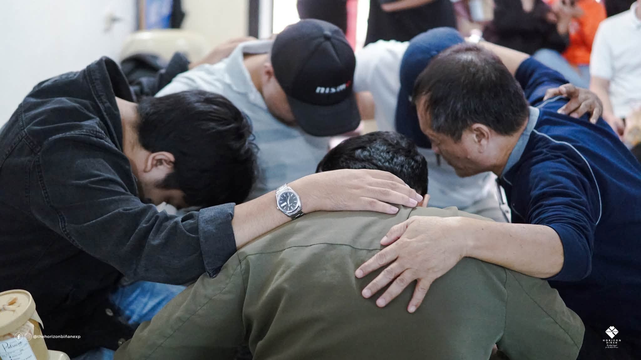 Men of Horizon Biñan huddled together in prayer, hands on each other’s shoulders.